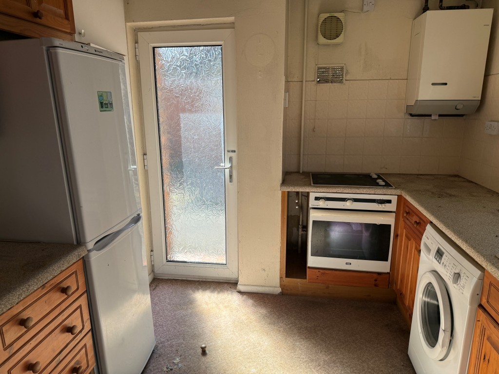 Lot: 128 - BUNGALOW WITH GARAGE AND GARDENS IN NEED OF MODERNISATION - Kitchen with window and glazed door to side access